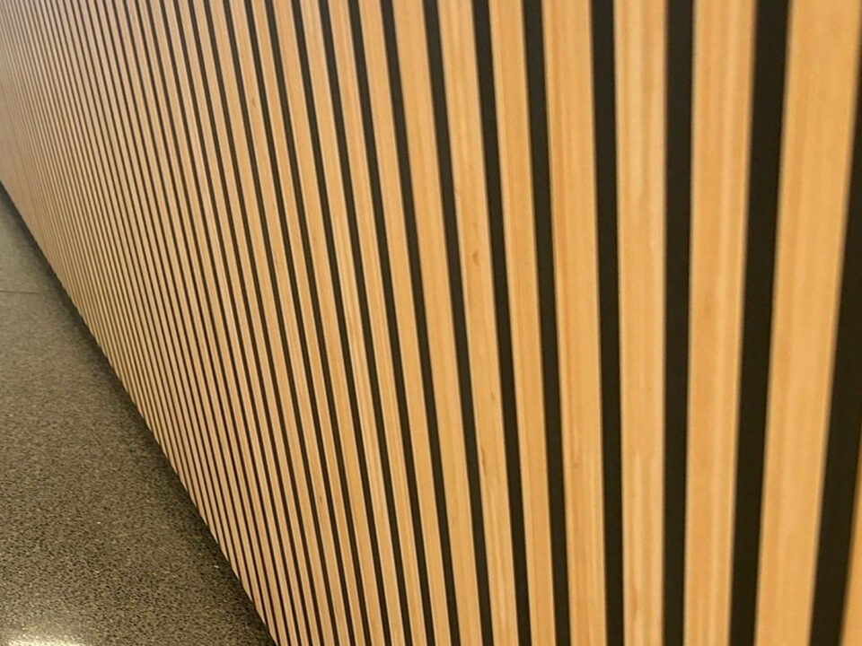 Detailfoto van houtlook interieurfolie met verticale zwarte lijnen op een winkeltoonbank