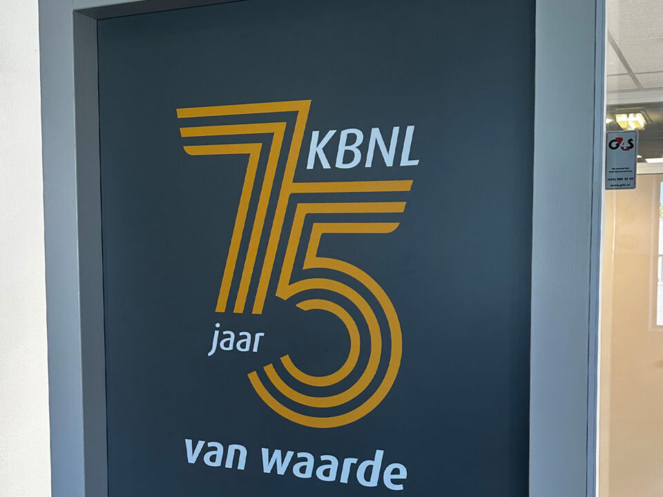 Jubileumlogo van Kredietbank Nederland als sticker op een donkere deur