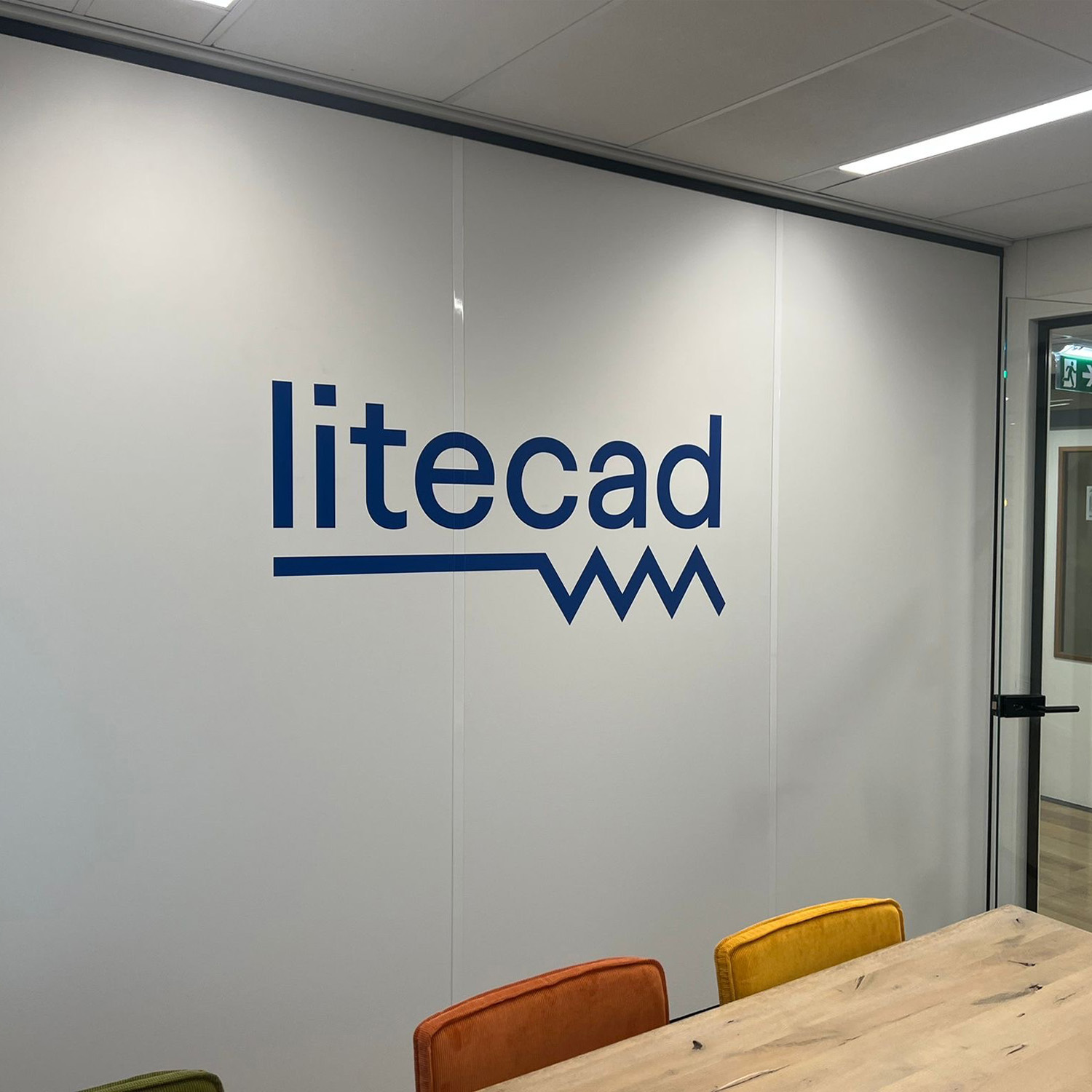Blauw Litecad-bedrijfslogo als grote muursticker op de wand van een vergaderruimte