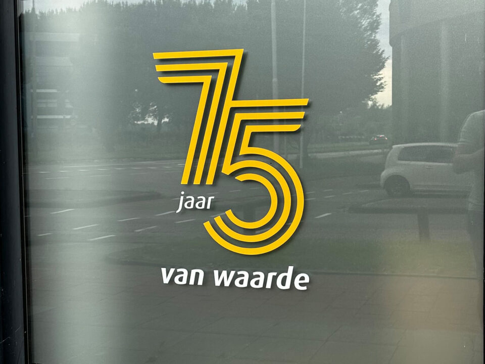 Gouden en witte jubileumsticker 75 jaar van waarde op een raam