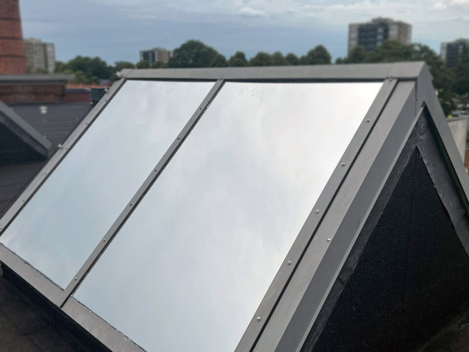 Detailfoto van reflecterende zonwerende buitenfolie op de schuine ruiten van een lichtstraat