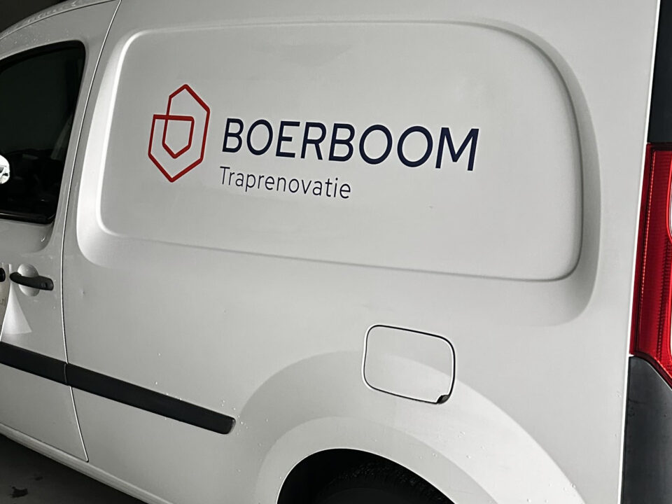 Rood beeldmerk en donkerblauwe belettering van Boerboom Traprenovatie op een witte bedrijfsbus