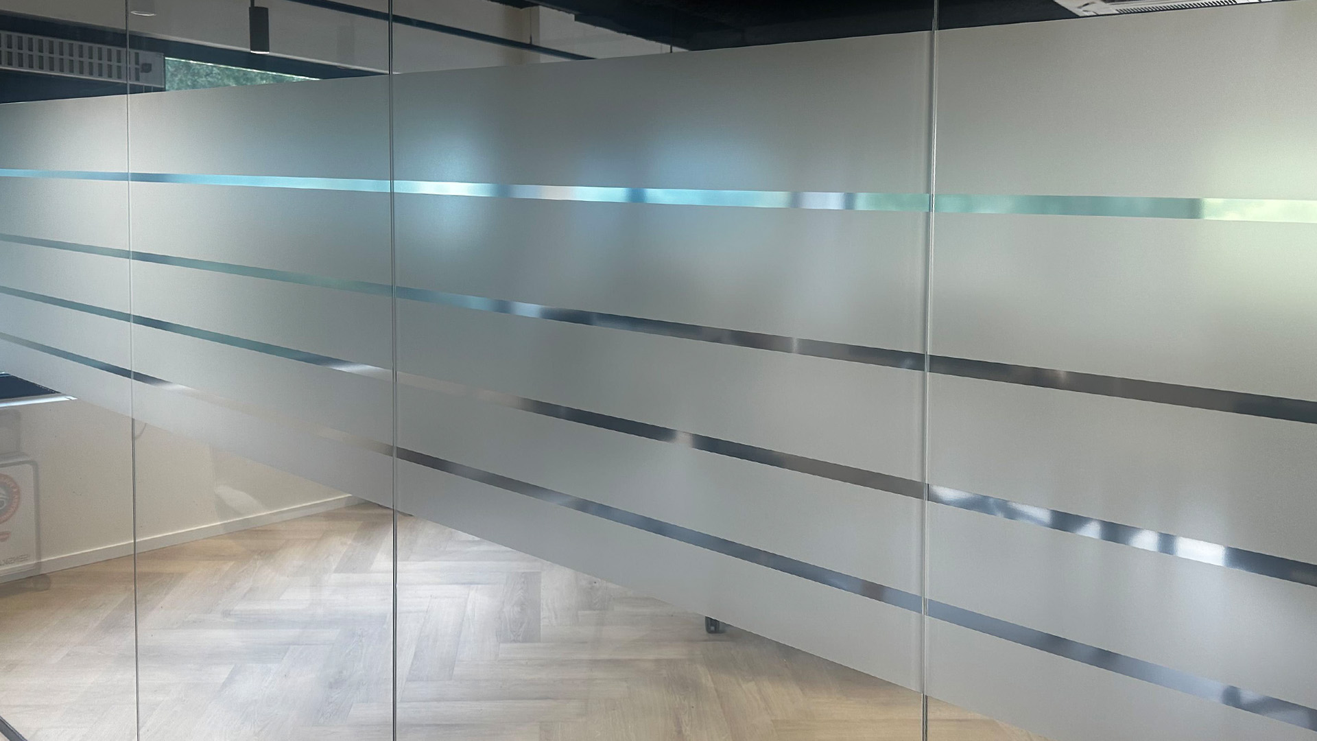 Brede matte privacyfolie met transparante strepen op een glazen wand bij Arbocentrum Ede