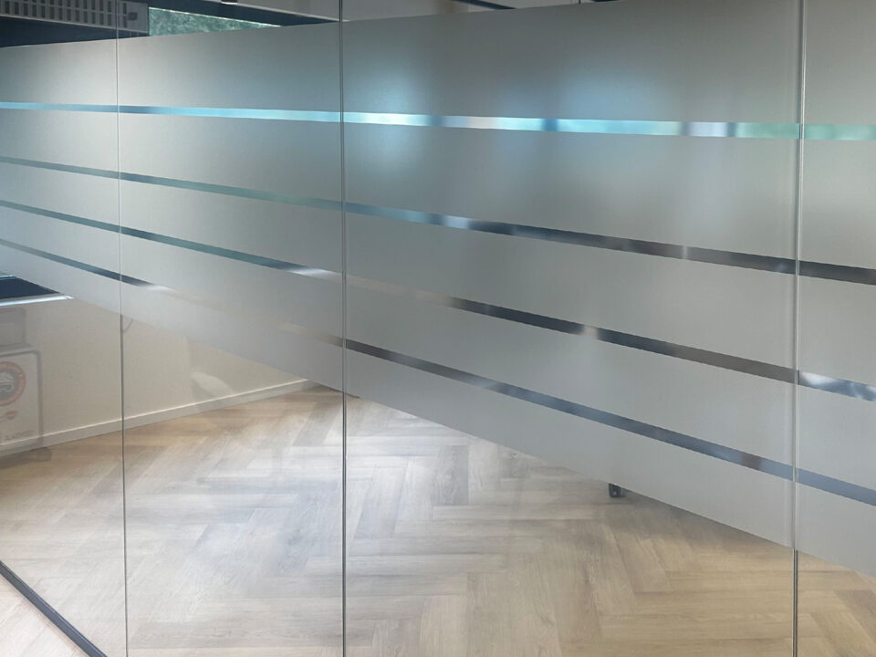 Detail van matte raamfolie met open strepen op glazen scheidingswand in Ede