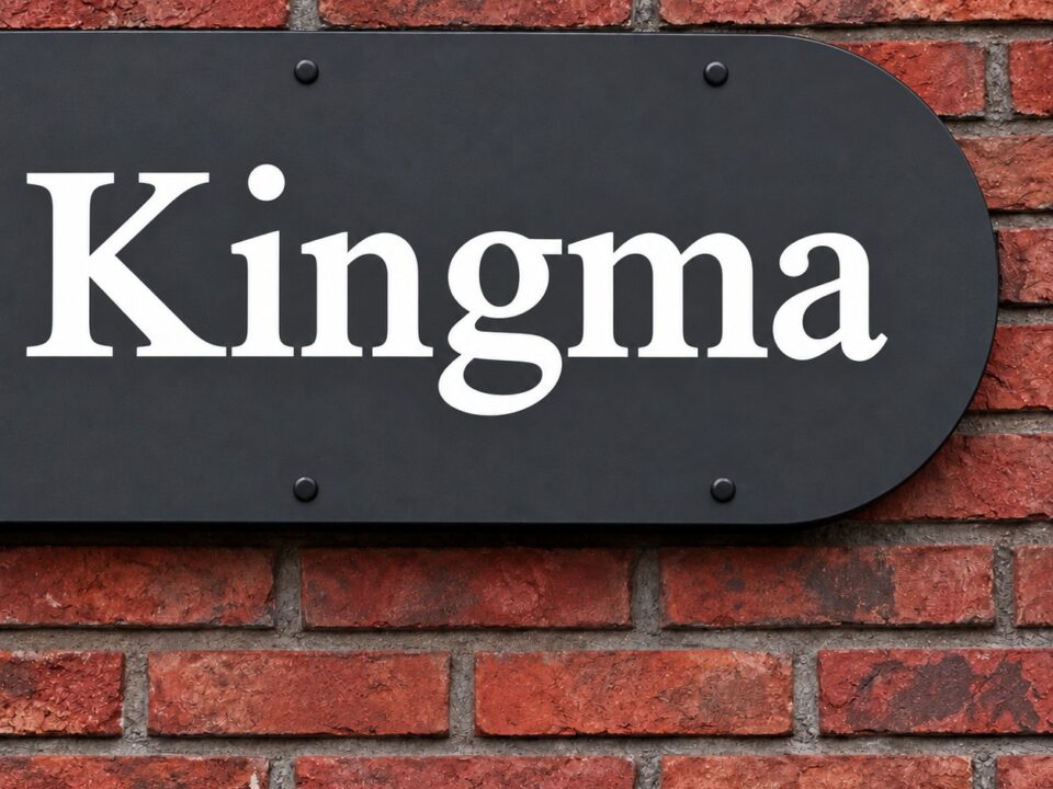 Detail van de witte naam Kingma op het zwarte gevelbord, met schaduw tussen het bord en de bakstenen gevel