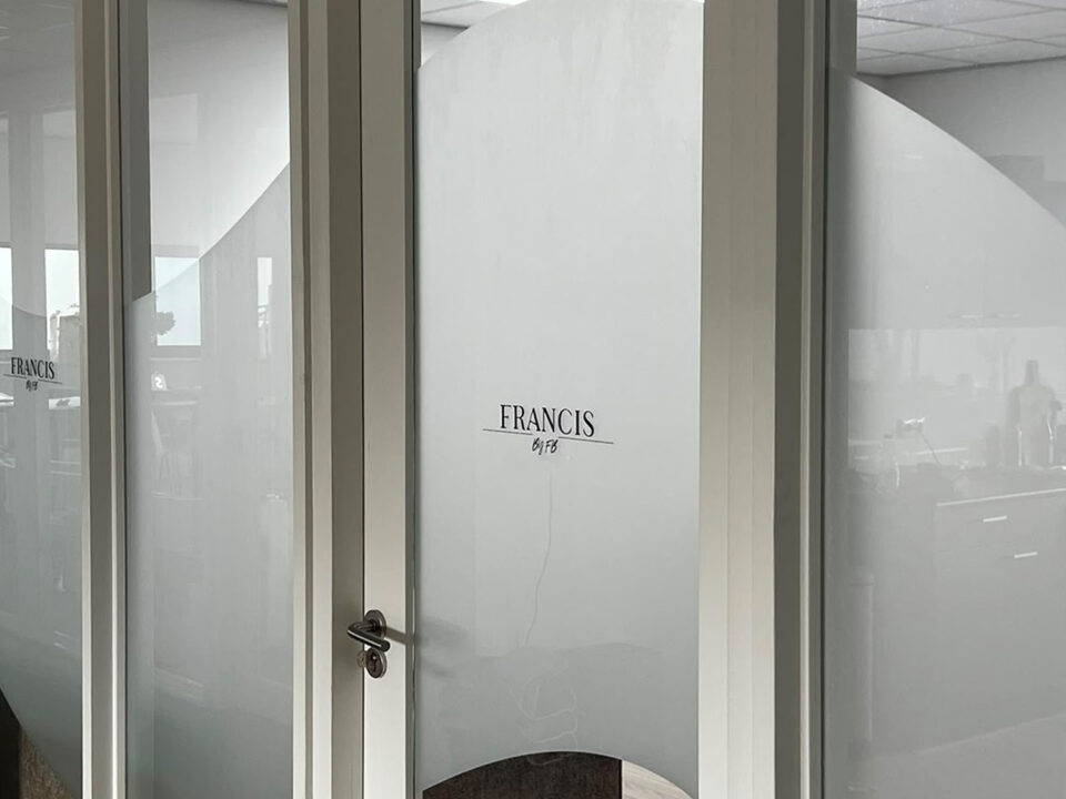 Golvende privacyfolie op een glazen kantoordeur en scheidingswand met zwart FRANCIS-logo